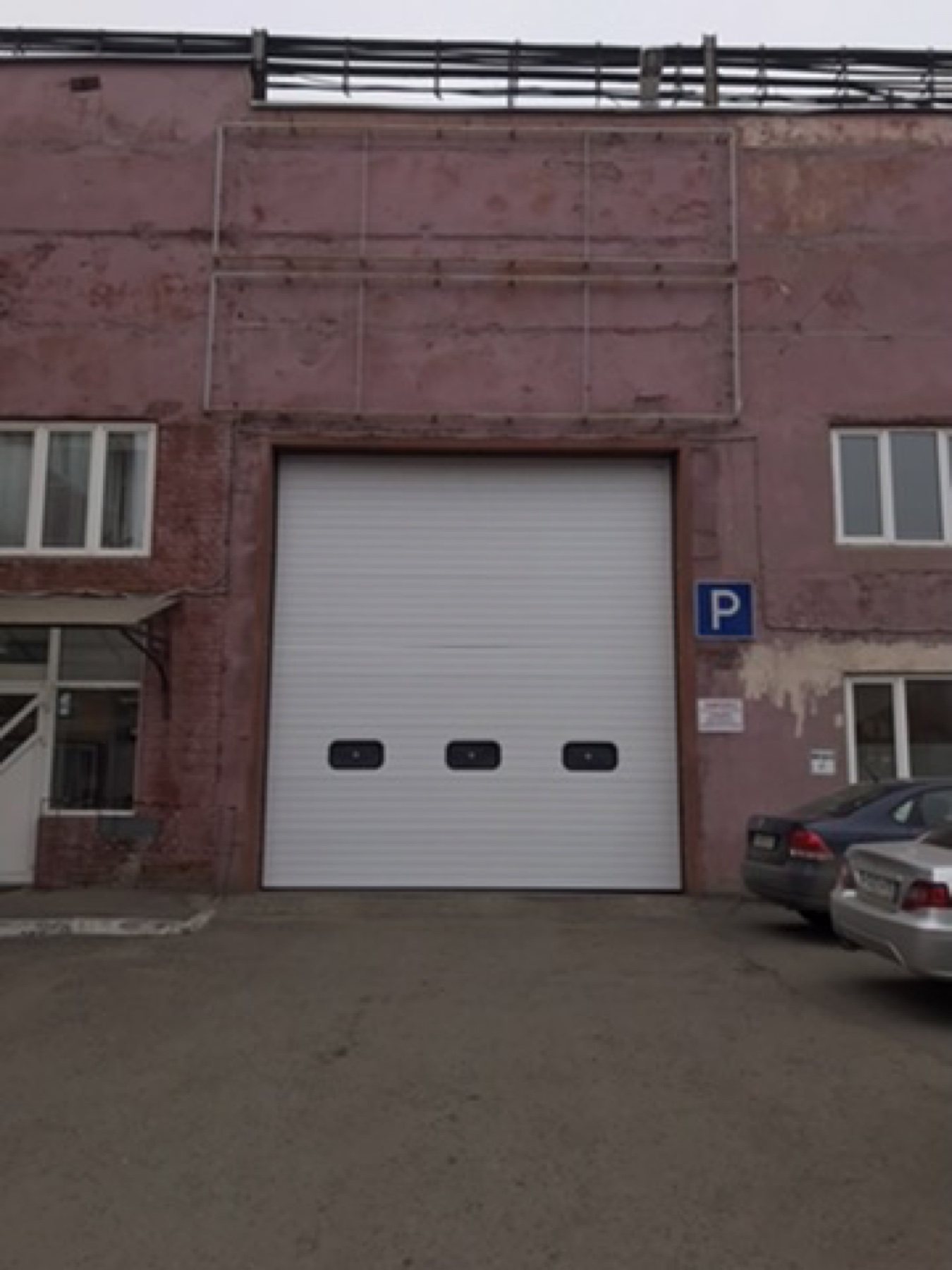 Белые промышленные ворота с окнами на фасаде предприятия